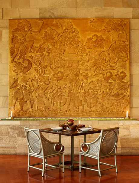 Circular dining table with two chairs beneath a large golden abstract artwork at Amanjiwo.