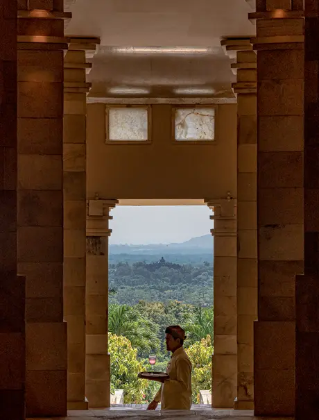 View through wooden temple doorway to terraced valleys at Amanjiwo