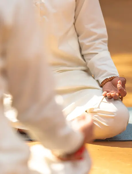 Hands in meditation pose at Amanjiwo, bathed in warm golden light.
