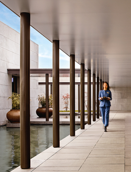 Visitor walking beneath wooden column structure at Amanyangyun gallery entrance.