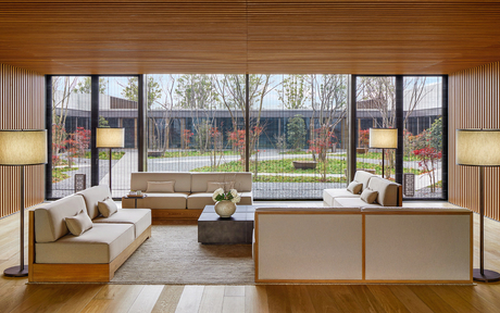 Amanyangyun gallery with floor-to-ceiling windows overlooking landscaped grounds and bare trees.