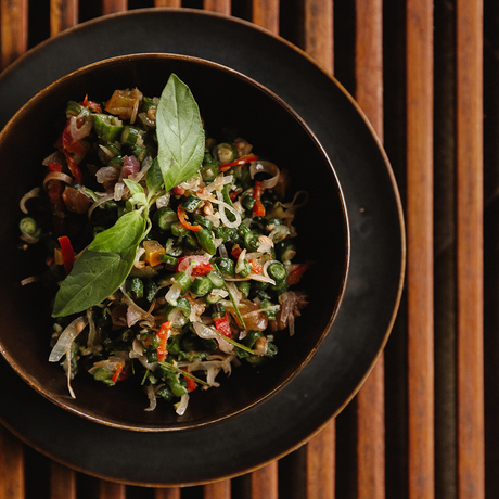 Overhead view of a noodle dish with vegetables and herbs in a black bowl at Amandari.