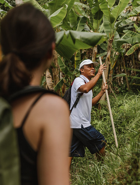 Staff member guiding a visitor through lush gardens at Amandari.