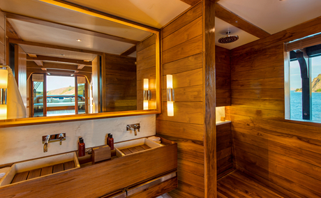 Wooden cabin bathroom at Amandira with dual vanity, mirror, and porthole windows.