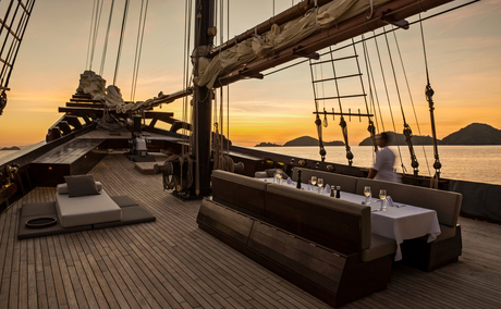 Foredeck of traditional wooden vessel at Amandira, Indonesia, at sunset with calm waters beyond.