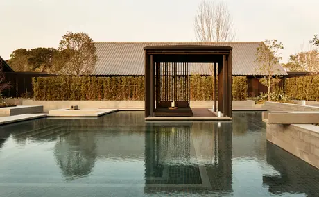 Amanemu resort wellness pavilion reflected in still pool at dusk.