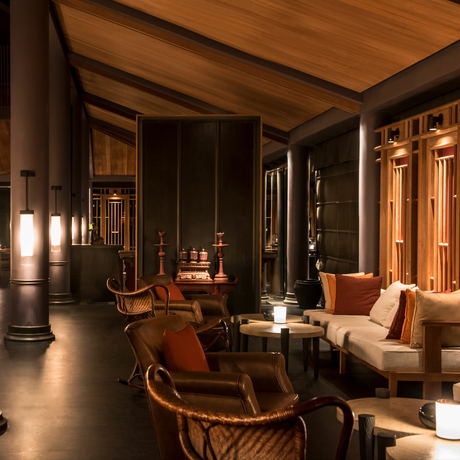 Amanoi lounge with warm wooden interiors, terracotta seating, and soft natural light filtering through architectural details.