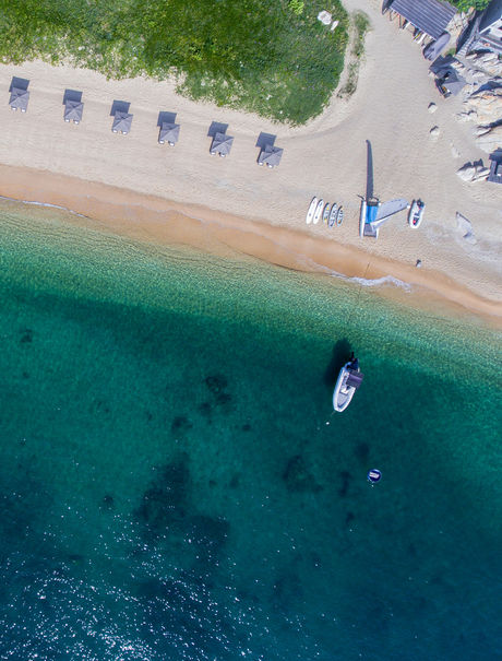 Aerial view of Amanoi's sandy beach with turquoise waters and moored boats.