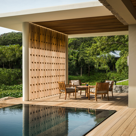 Wooden pavilion overlooking a plunge pool at Amanoi, with latticed screens and dining furniture nestled amongst verdant surroundings.
