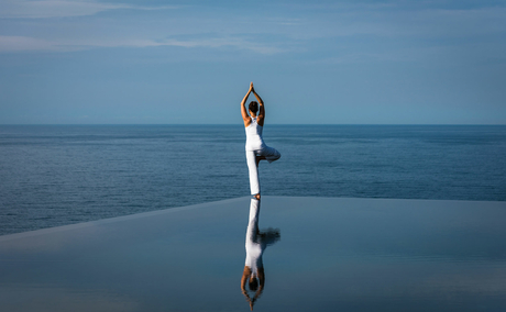 Woman in white dress standing on still water at Amanoi, reflected in the surface below.