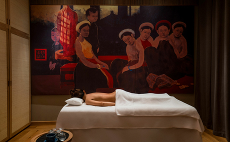 Spa treatment room at Amanoi with massage table, folded towels, and artwork on wall.