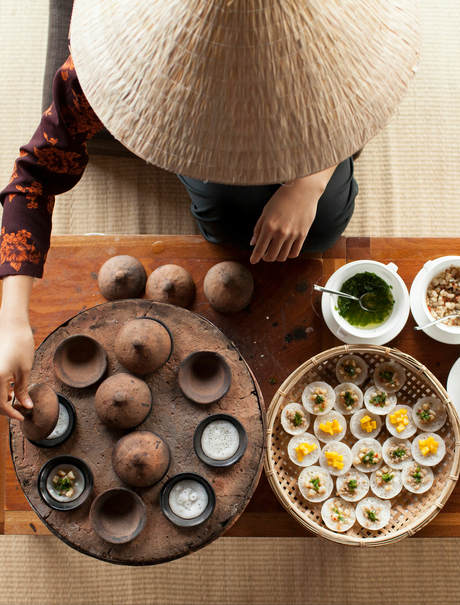 Overhead view of a traditional Vietnamese conical hat beside a wooden tray of quail eggs and bowls of ingredients at Amanoi.