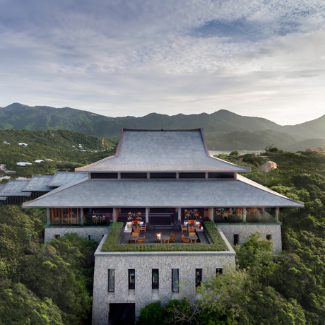 Amanoi's architectural pavilion with sweeping roof overlooks forested valley and distant mountains.