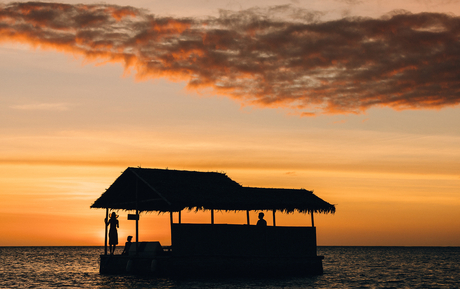 Silhouetted wooden boat structure against golden sunset sky at Amanpulo.