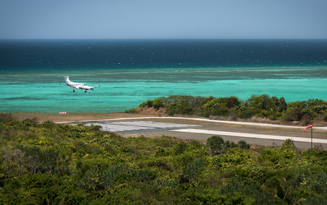 Turquoise lagoon with moored boat and forested island at Amanpulo.