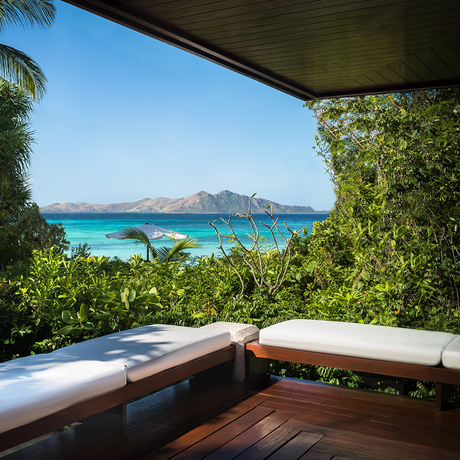 Wooden deck with cushioned seating overlooking turquoise waters and islands at Amanpulo.