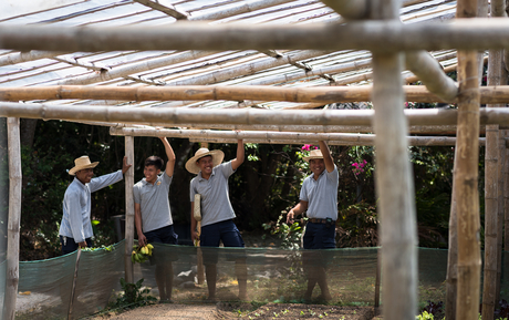 Visitors exploring the open-air pavilion at Amanpulo, with natural light filtering through the wooden framework.