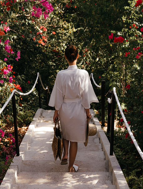 Guest walking along a white stone pathway bordered by vibrant flowering vines at Amanpulo.