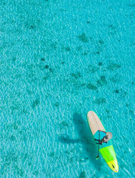 Kayaker paddling through turquoise waters at Amanpulo resort.