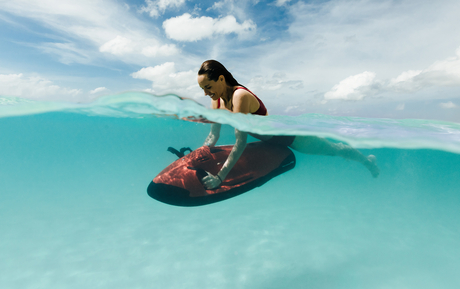 Woman on traditional wooden boat in turquoise waters at Amanpulo.