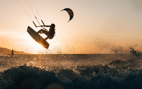Kite surfer in action at Amanpulo at sunset over calm waters.