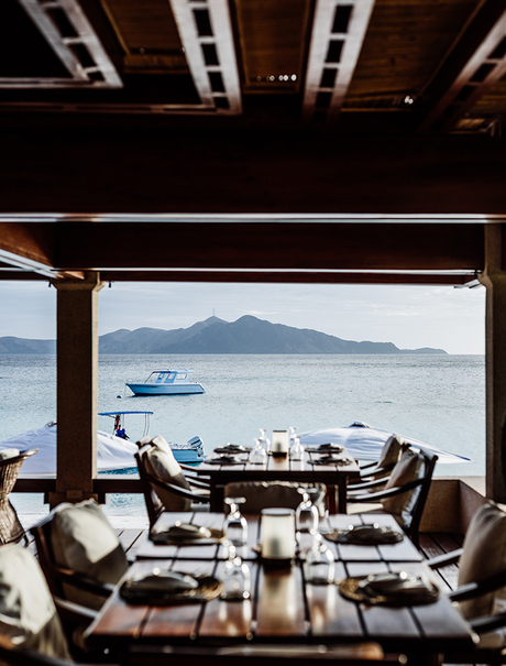 Amanpulo dining venue with wooden ceiling overlooking calm waters and distant mountain peaks.