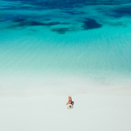 Aerial view of a guest on a red and white boat in the turquoise waters surrounding Amanpulo.