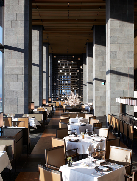 Arva dining venue at Aman Tokyo, with soaring concrete columns and warm lighting overhead.