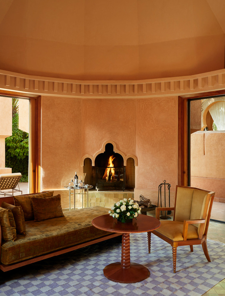 Amanjena pavilion interior with curved terracotta walls, fireplace and seating area overlooking gardens.