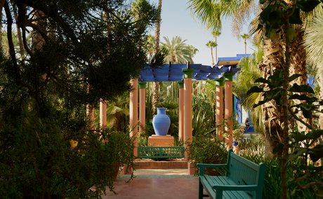 Verdant garden pathway at Amanjena with illuminated archway at dusk.