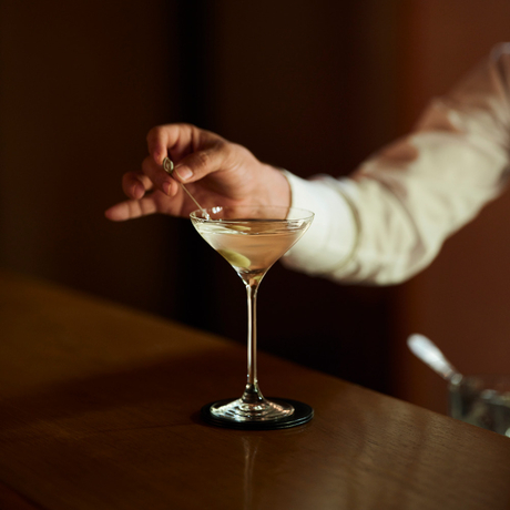 Hand holding a cocktail glass at Amanjena.