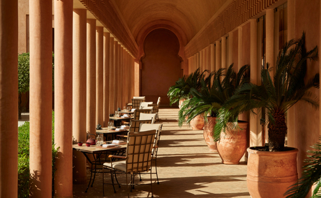 Colonnade at Amanjena with arched ceiling, classical columns, and terracotta urns lining a peaceful corridor.