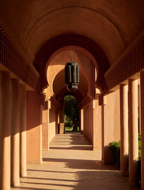 Arched corridor at Amanjena with warm golden light casting shadows across colonnade.