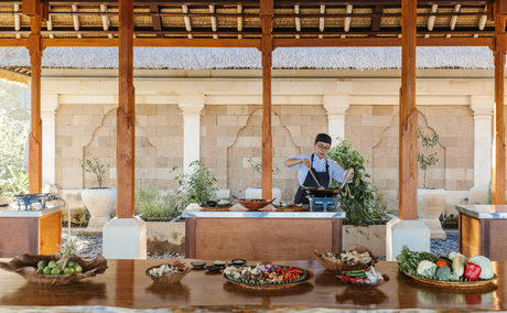 Chef instructing guests during a cooking class at Amankila, with open-sided pavilion overlooking tropical gardens.