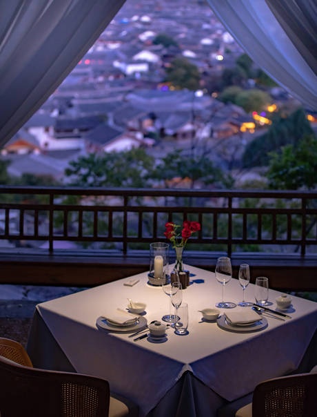 Dining table set for two at Amandayan with valley views illuminated at dusk.