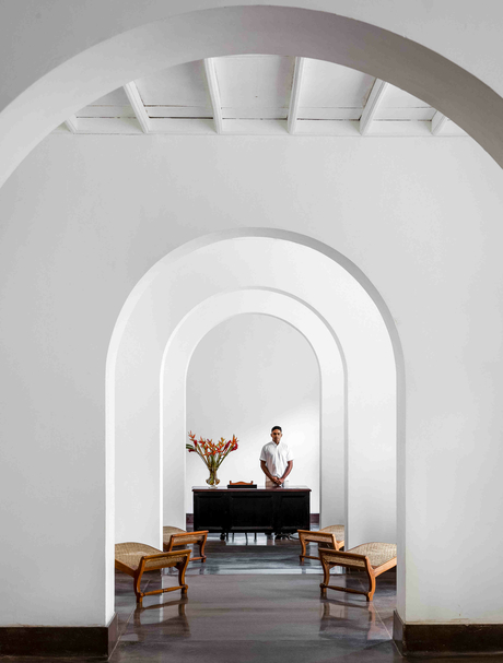 Ben Richards photograph of a vaulted corridor at Amangalla with a piano and wooden chairs visible through the archway.