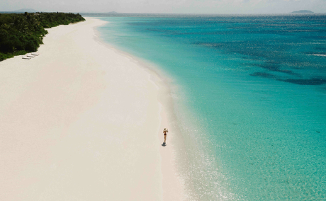 Aerial view of a solitary figure on a pristine white sand beach with turquoise waters at Amanpulo.