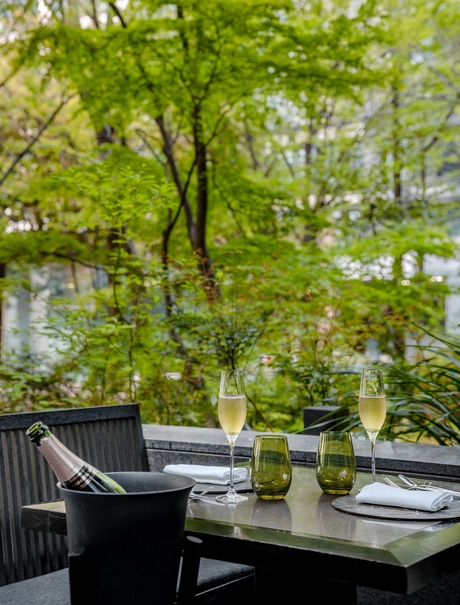Spring garden view at Aman Tokyo with dining table beneath flowering trees.