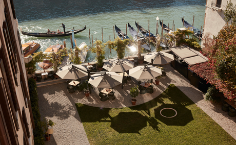 Aman Venice garden with stone seating areas overlooking the lagoon and distant boats.