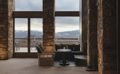 Grand Staircase Lobby at Amangani with wooden columns framing mountain views through floor-to-ceiling windows.