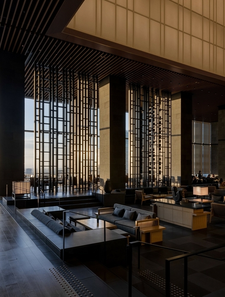 Autumn light filters through wooden screens in Aman Tokyo's serene lounge, with low seating and dark architectural lines.