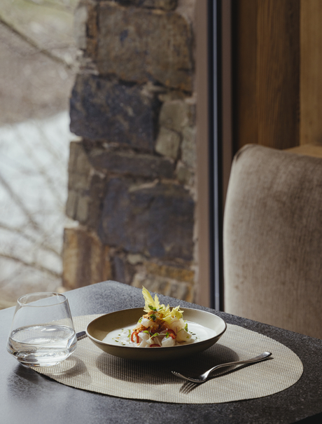 Minimalist table setting at Amangani with a small brass bowl and white marble surface against stone wall.