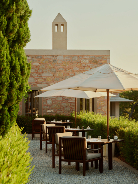 Poolside dining terrace at Amanruya with stone architecture, shaded seating and verdant landscaping.