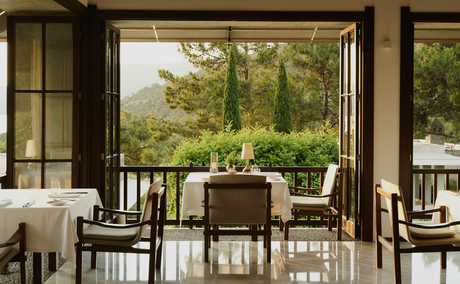 Private dining room at Amanruya overlooking verdant Turkish landscape through open doors.