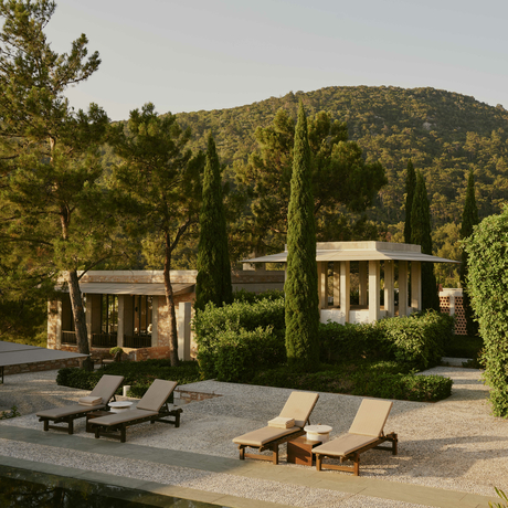 Amanruya's main pool terrace with loungers and pavilions set against forested hillside architecture in Turkey.