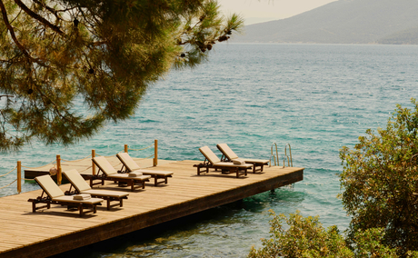 Wooden deck with sun loungers overlooking turquoise waters at Amanruya, Turkey.
