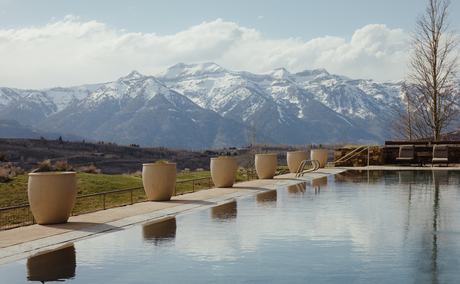 Infinity pool at Amangani overlooking snow-capped mountain range at dusk.