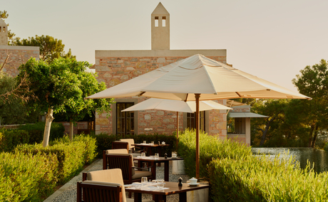 Dining poolside terrace at Amanruya with shaded seating, greenery, and countryside views at dusk.