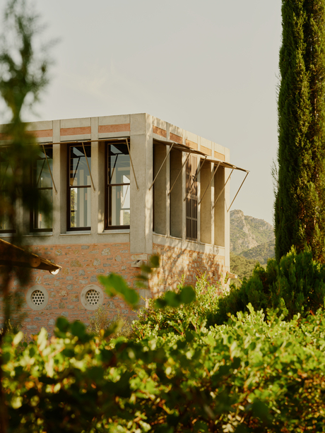 Library Tower at Amanruya, a stone structure framed by cypress trees and green hedges, in Turkey.