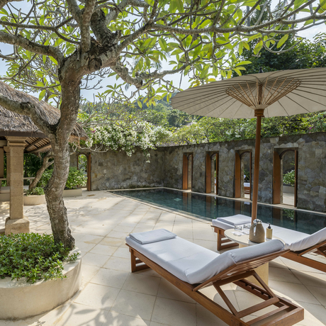 Pool Suite courtyard at Amankila, Indonesia, with loungers beneath mature trees and pavilion shelter.